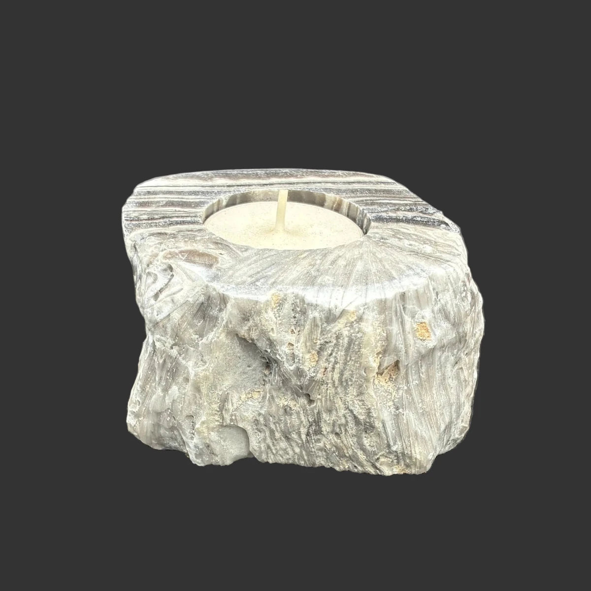 This is the right side of this zebra calcite candle holder in front of a black background.
