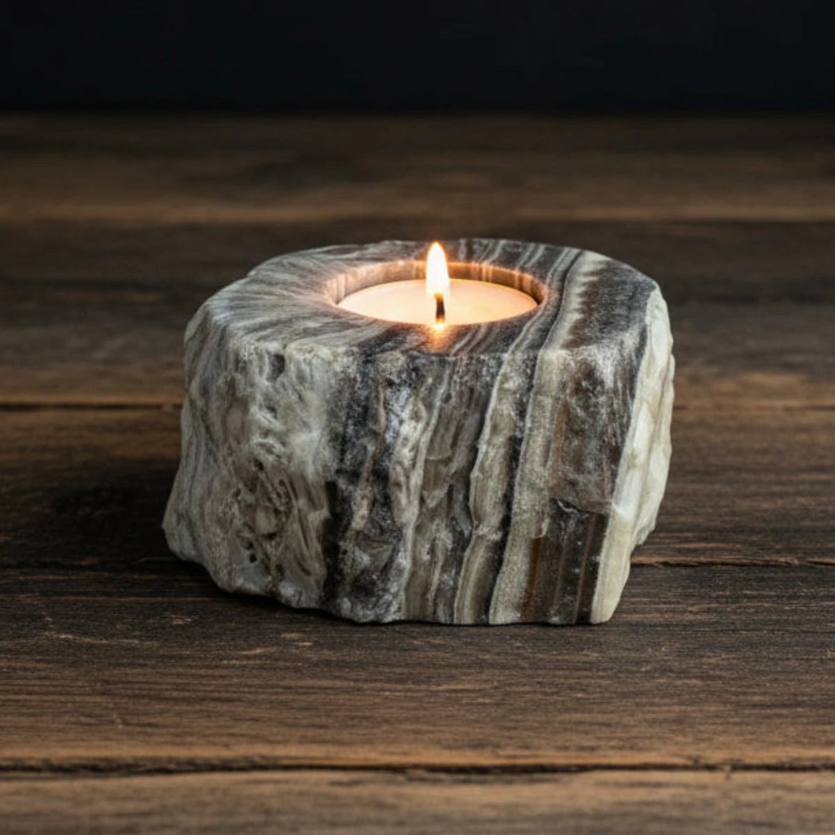 This zebra calcite candle holder, with the candle lite, and on a table top.
