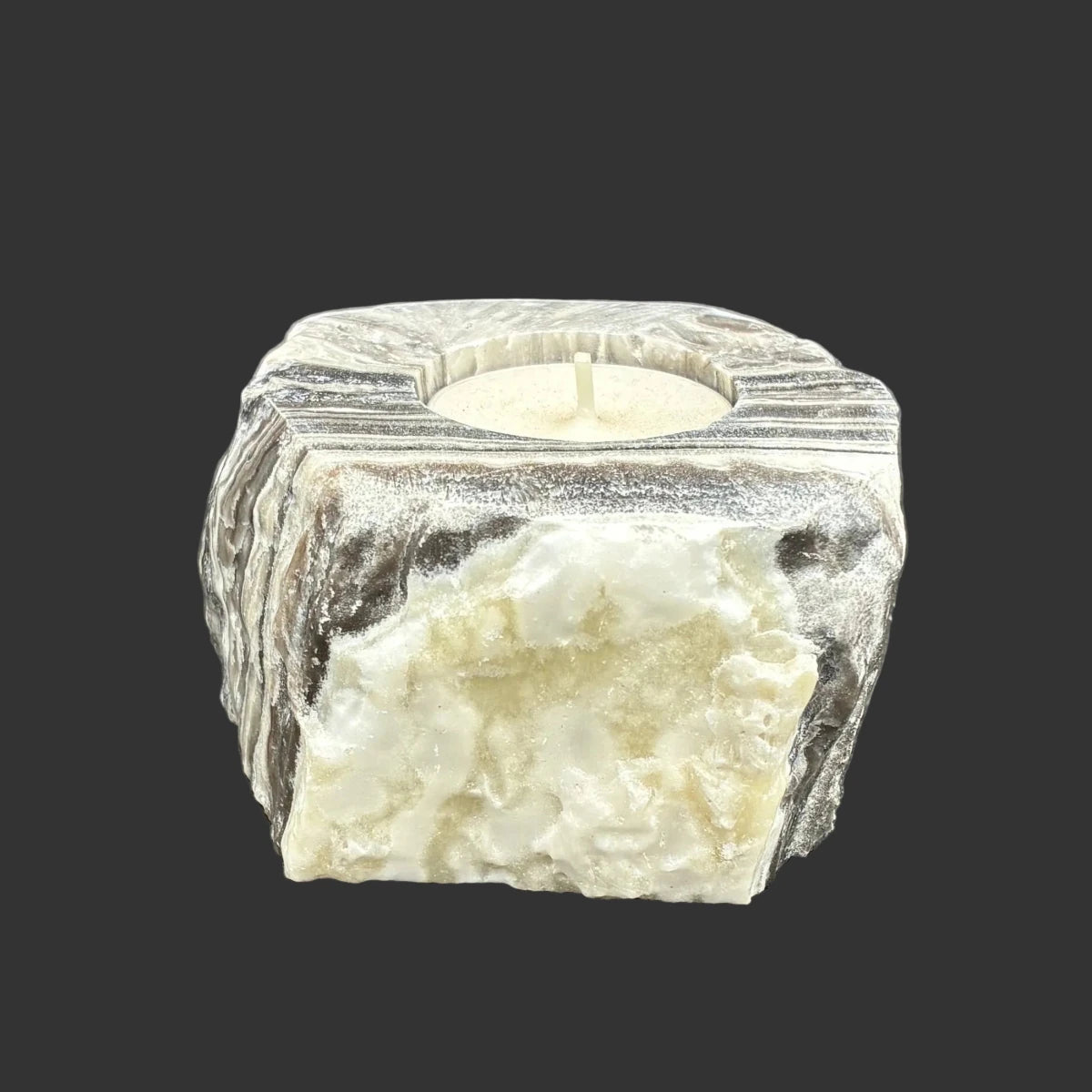 Left side of this zebra calcite candle holder, in front of a black background.
